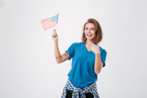 Cheerful young girl student pointing finger at american flag